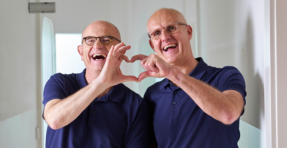 Zahnarzt Dr. Frank und Dr. Pflumm lachen und bilden mit ihren Händen ein Herz Zahnarzt Dr. Frank und Dr. Pflumm lachen und bilden mit ihren Händen ein Herz