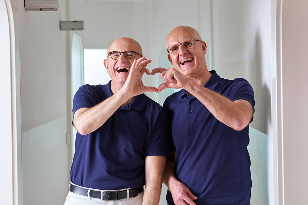 Frank Pflumm Zahnärzte mit Herz Zahnarzt Dr. Frank und Dr. Pflumm lachen und bilden mit ihren Händen ein Herz
