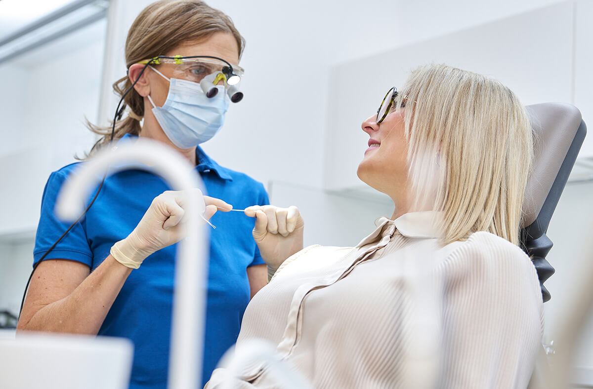 Zahnmedizinische Prophylaxe-Assistentin mit Patientin bei der Zahnreinigung mit Zahnseide